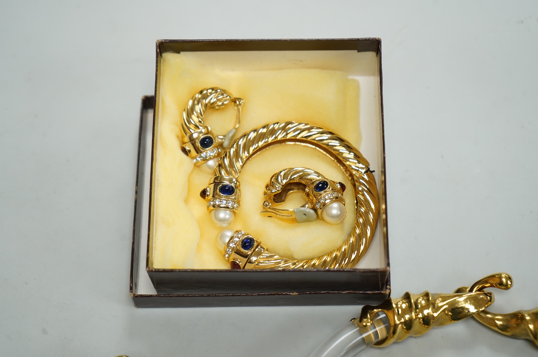 A small group of assorted costume jewellery including a 925 and paste set brooch and pair of ear clips and a gilt metal charm bracelet.